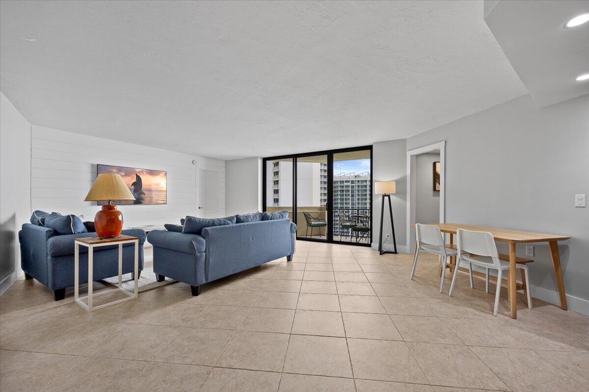 A living room with blue sofas, tile flooring, and a sliding glass door to a balcony — 2800 N Ocean Drive # 18c, Riviera Beach FL 33404, RIVIERA BEACH, FL