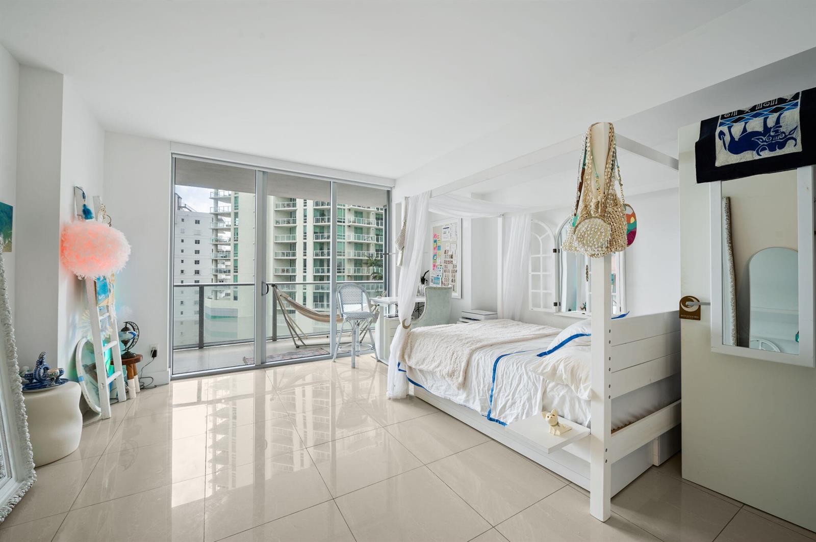An open-plan living area features light tile flooring, white walls, and a compact modern kitchen — 1300 Brickell Bay Drive # 1005, Miami FL 33131, MIAMI, FL