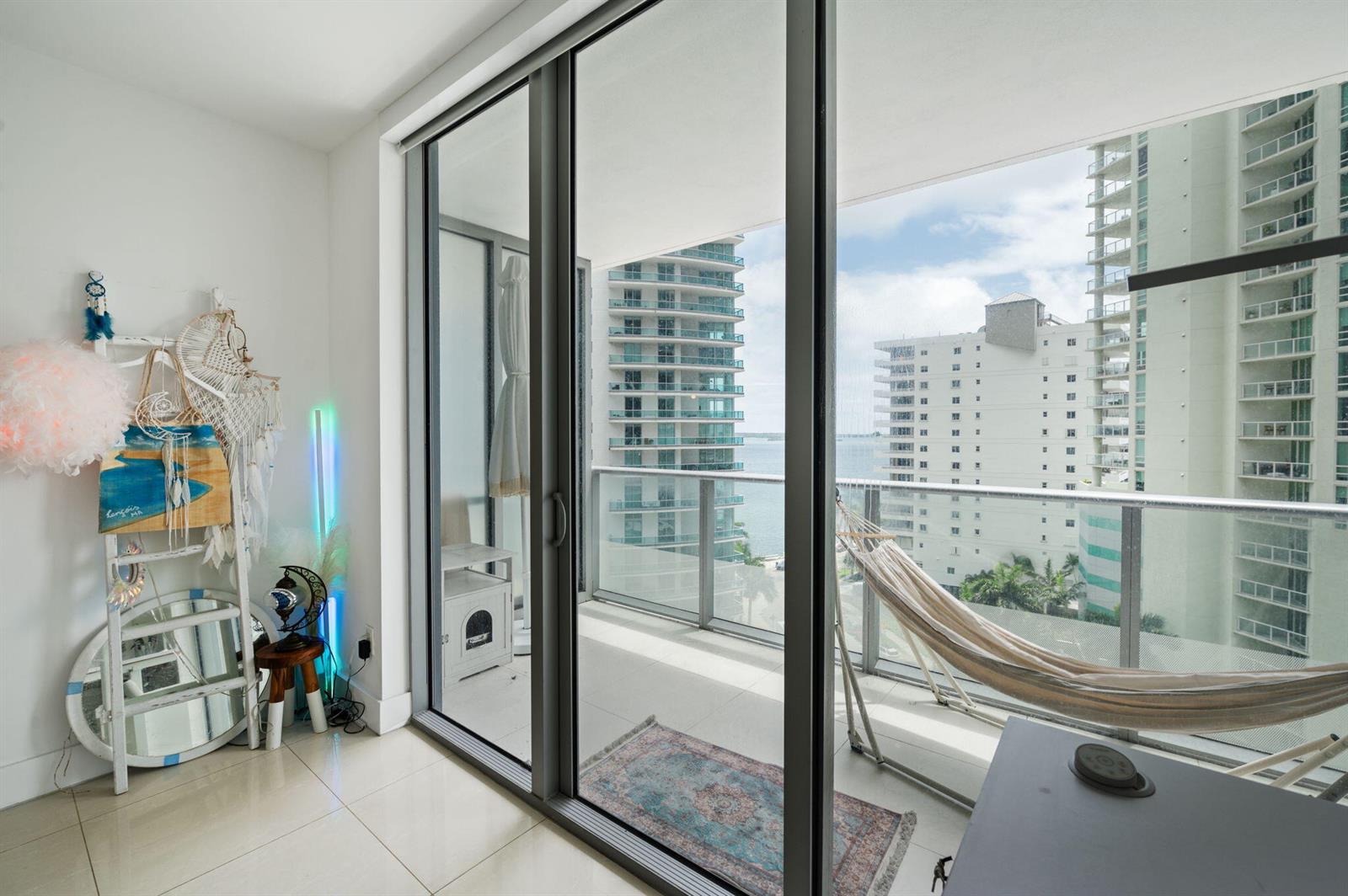 An empty living area with white walls, tile flooring, a closet, and an adjacent kitchen — 1300 Brickell Bay Drive # 1005, Miami FL 33131, MIAMI, FL