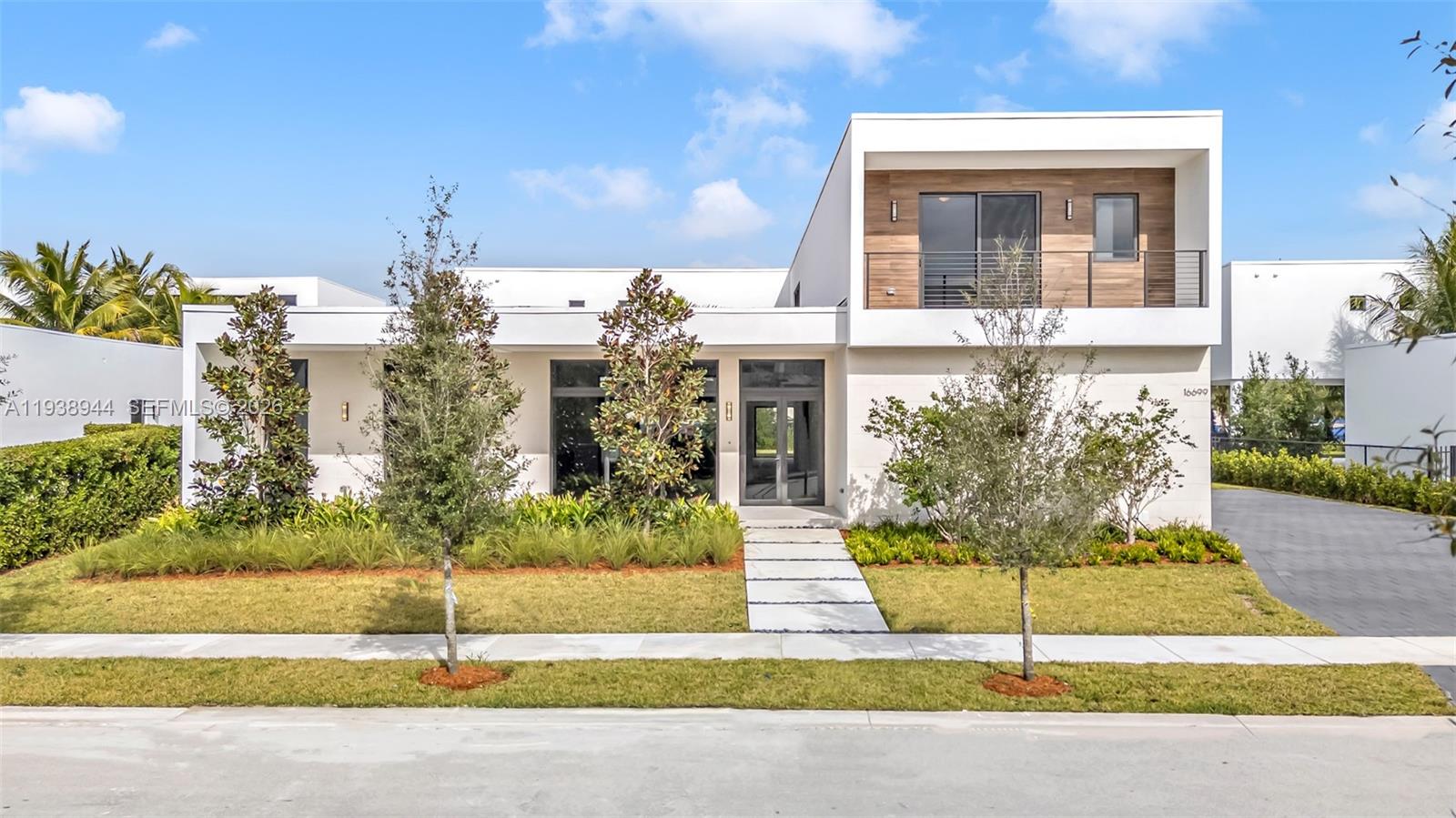 A modern two-story house features a white exterior, wood-paneled balcony, and a paved walkway — 16699 N Botaniko Dr N, Weston FL 33326, WESTON, FL