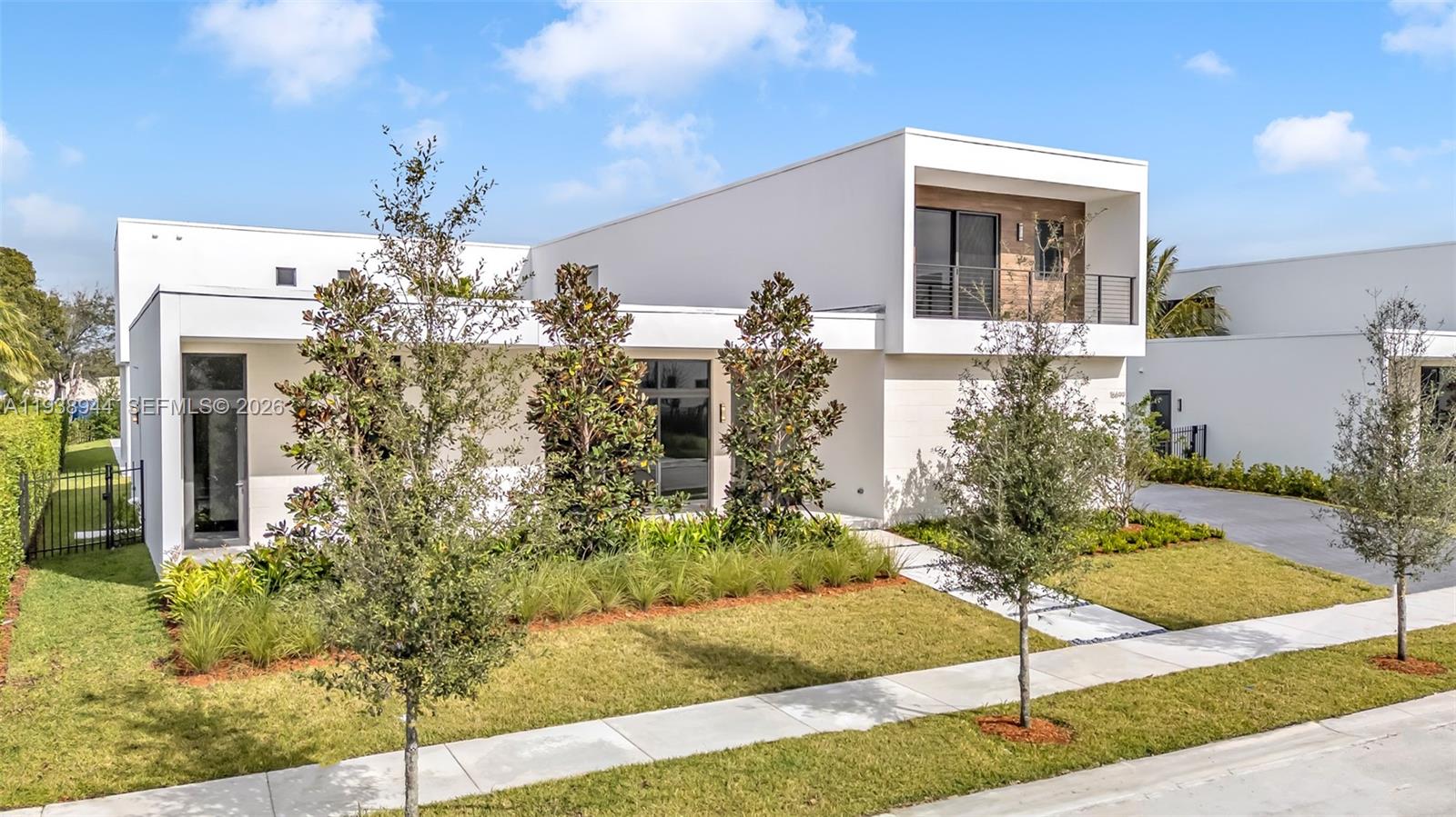 A modern two-story white house features a flat roof, a balcony, and landscaped front yard — 16699 N Botaniko Dr N, Weston FL 33326, WESTON, FL