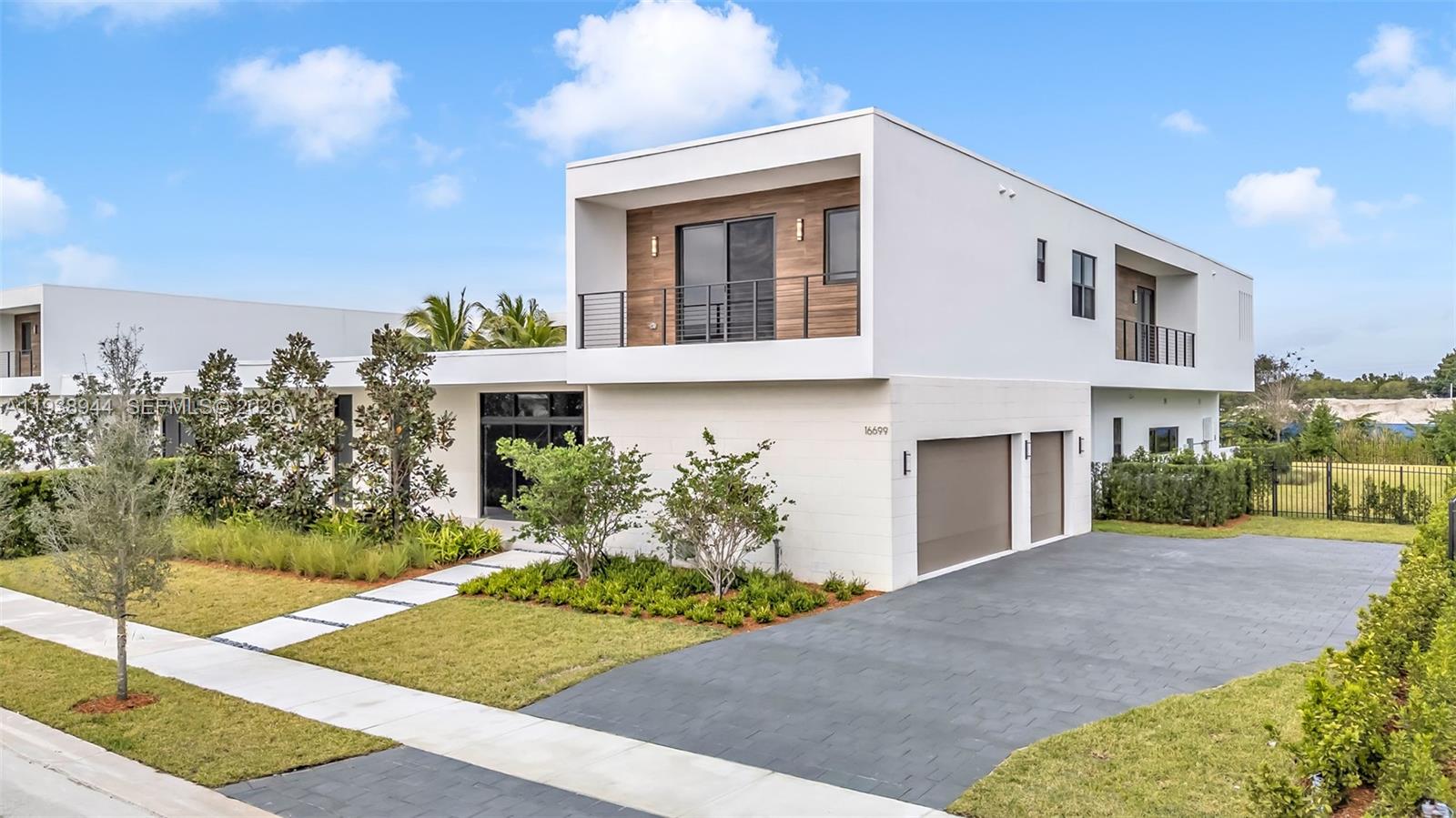 A modern two-story house with a white exterior, wood accents, and a paved driveway — 16699 N Botaniko Dr N, Weston FL 33326, WESTON, FL