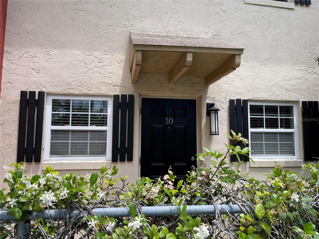 The exterior of a tan building features a black front door numbered ten and shutters — 2501 E CENTRAL BOULEVARD UNIT 10, ORLANDO, FL