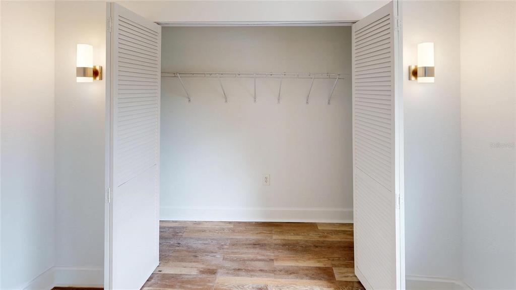 A closet with louvered doors, a wire shelf, and wood-look flooring — 2501 E CENTRAL BOULEVARD UNIT 10, ORLANDO, FL