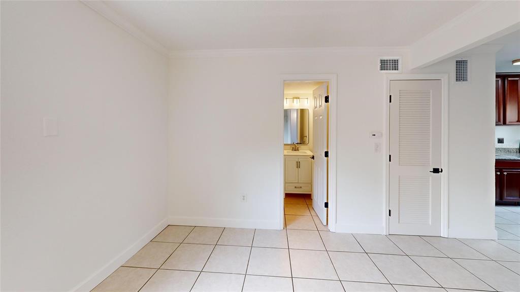 A room with light-colored tile flooring, a doorway leading to a bathroom, and a closet — 2501 E CENTRAL BOULEVARD UNIT 10, ORLANDO, FL