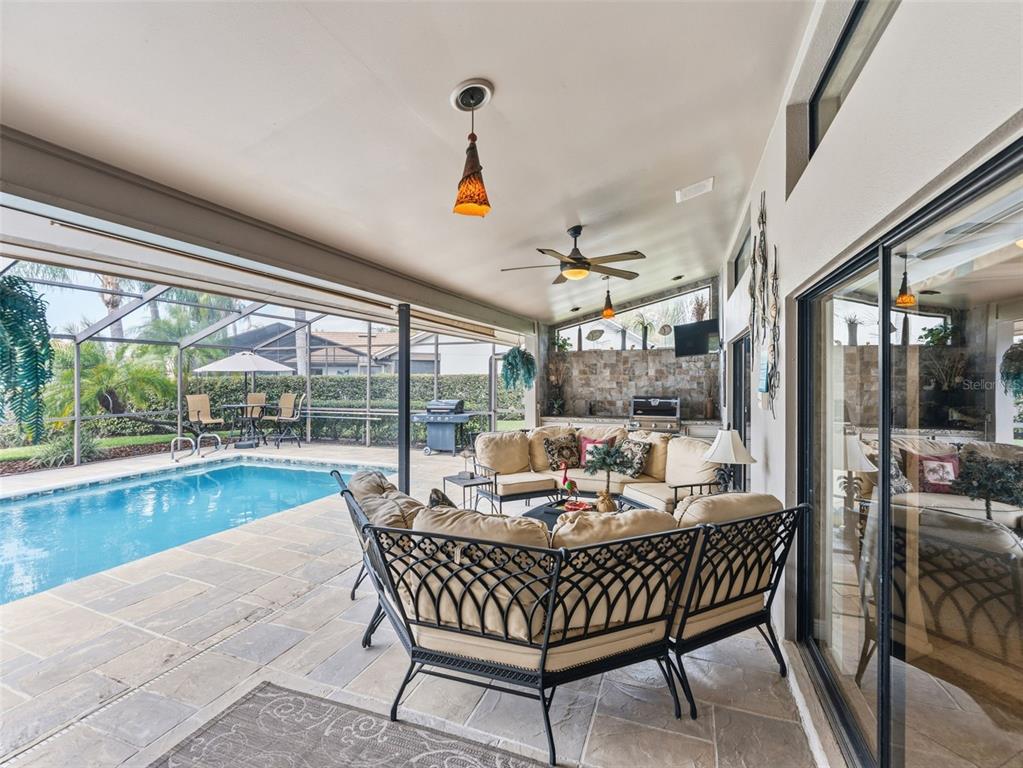 A covered patio features a swimming pool, outdoor kitchen, and curved seating area — 4830 LONGWATER WAY, TAMPA, FL