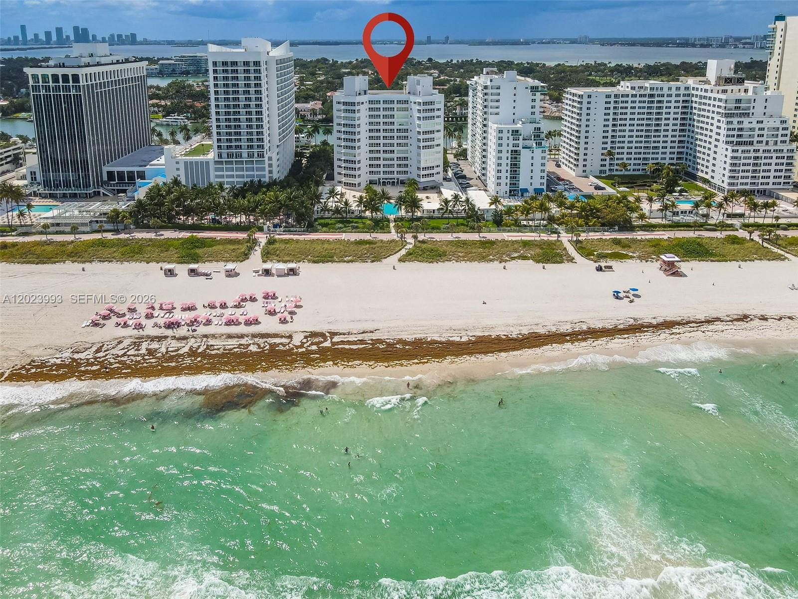 An aerial view shows a white high-rise building on a sandy beach with oceanfront access — 4925 Collins Ave # 11E, Miami Beach FL 33140, MIAMI BEACH, FL