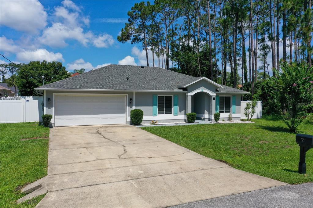 A single-story house with a gray exterior, white trim, and a concrete driveway — 21 LAKE CHARLES LANE, PALM COAST, FL