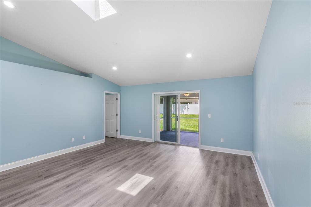 A living room with light blue walls, gray wood-look flooring, and a sliding glass door — 21 LAKE CHARLES LANE, PALM COAST, FL