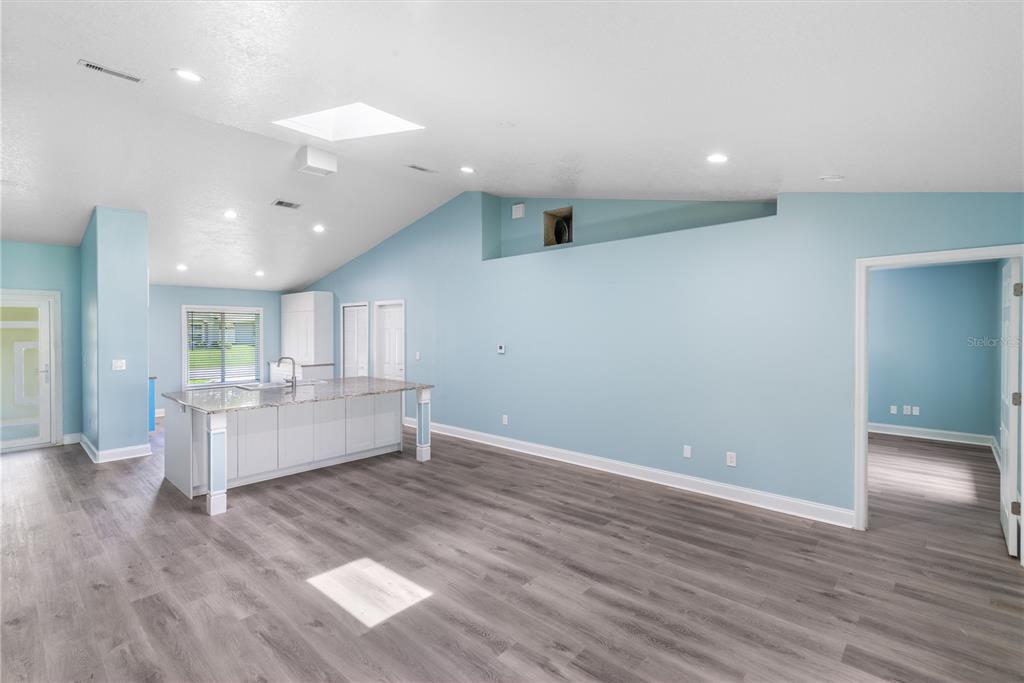 An open-concept kitchen and living area features light blue walls, gray flooring, and a skylight — 21 LAKE CHARLES LANE, PALM COAST, FL