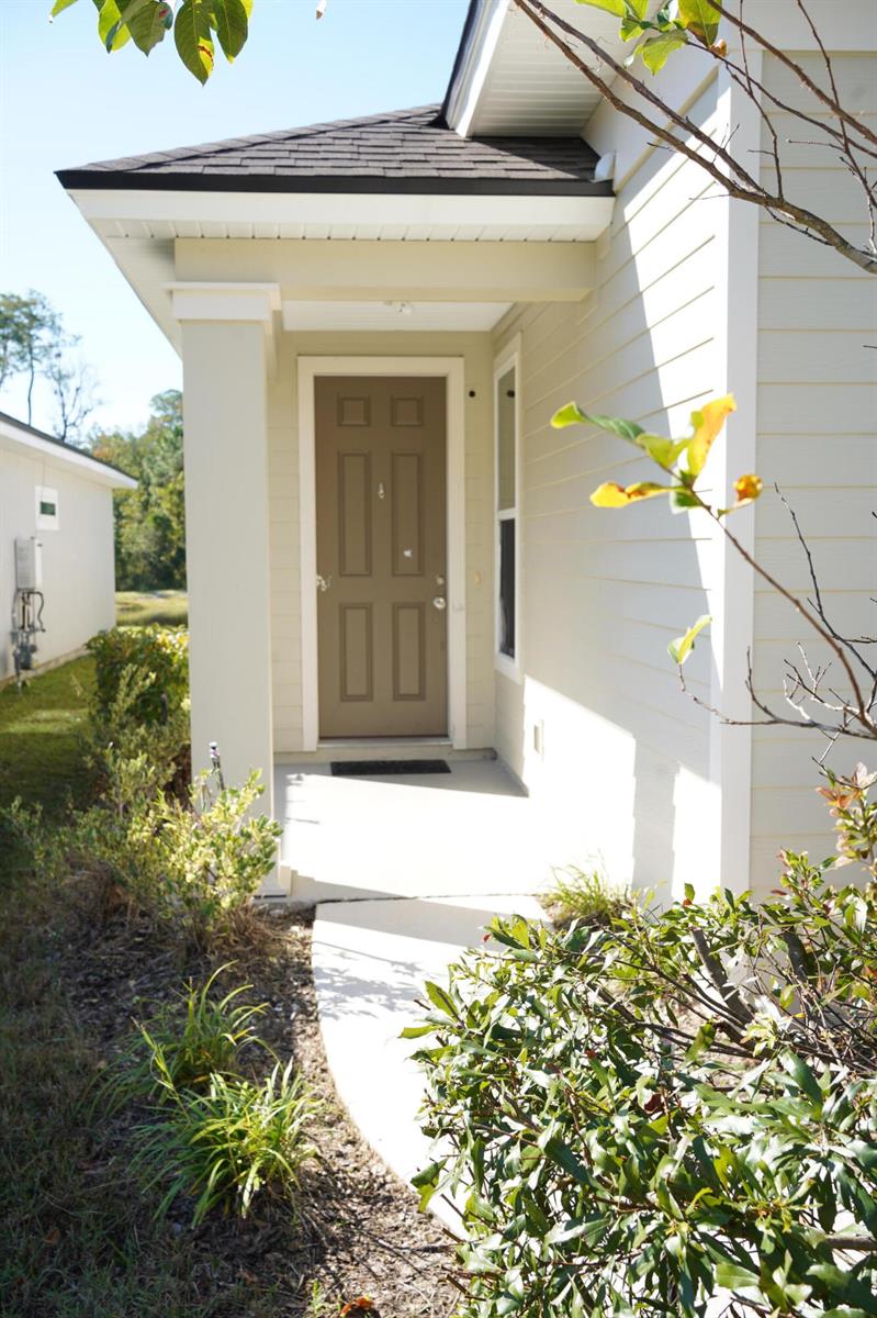 A tan house exterior features a brown front door under a covered porch entryway — 855 Sycamore Way, FL 32073, FL