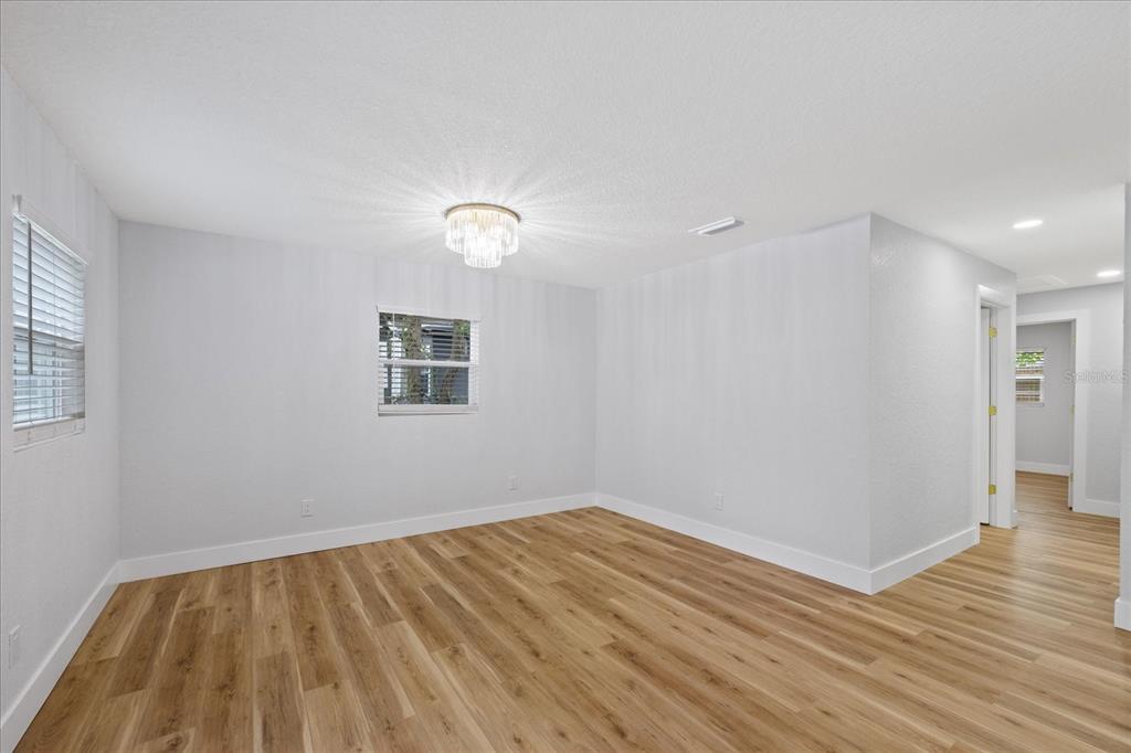 An empty room features light gray walls, white trim, and wood-look flooring — 3621 E COMANCHE AVENUE, TAMPA, FL