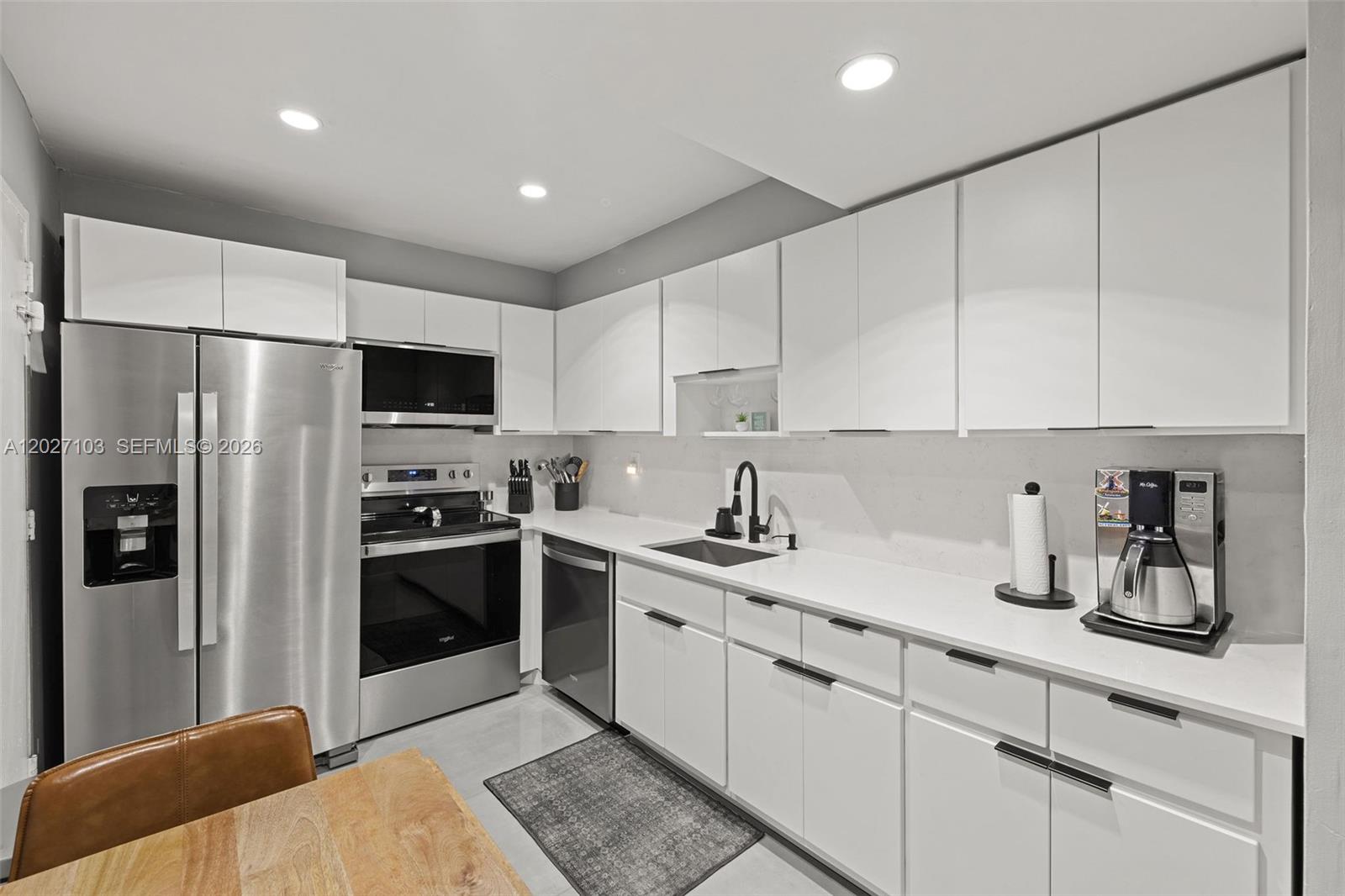 A modern kitchen features white cabinets, stainless steel appliances, and white countertops — 5001 Collins Ave # 1E, Miami Beach FL 33140, MIAMI BEACH, FL