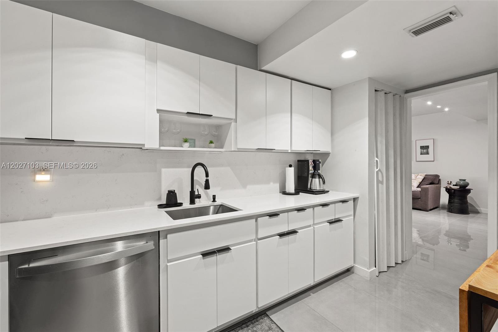 A modern kitchen features white cabinets, stainless steel appliances, and a white countertop — 5001 Collins Ave # 1E, Miami Beach FL 33140, MIAMI BEACH, FL