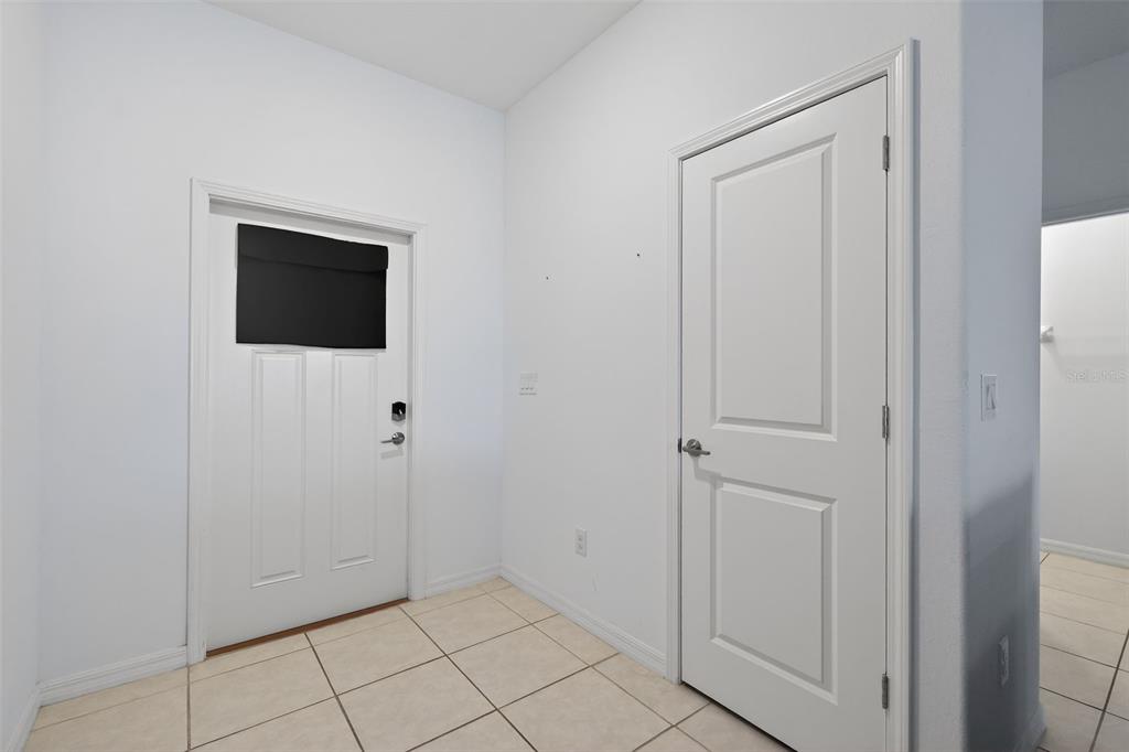 An entryway features a white door with a black window cover and tiled flooring — 32021 POWDERPUFF MIMOSA DRIVE, SAN ANTONIO, FL
