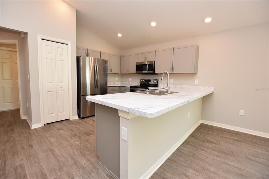 A kitchen features gray cabinets, stainless steel appliances, and a white marble-patterned island countertop — 372 CASCARA LANE, AUBURNDALE, FL