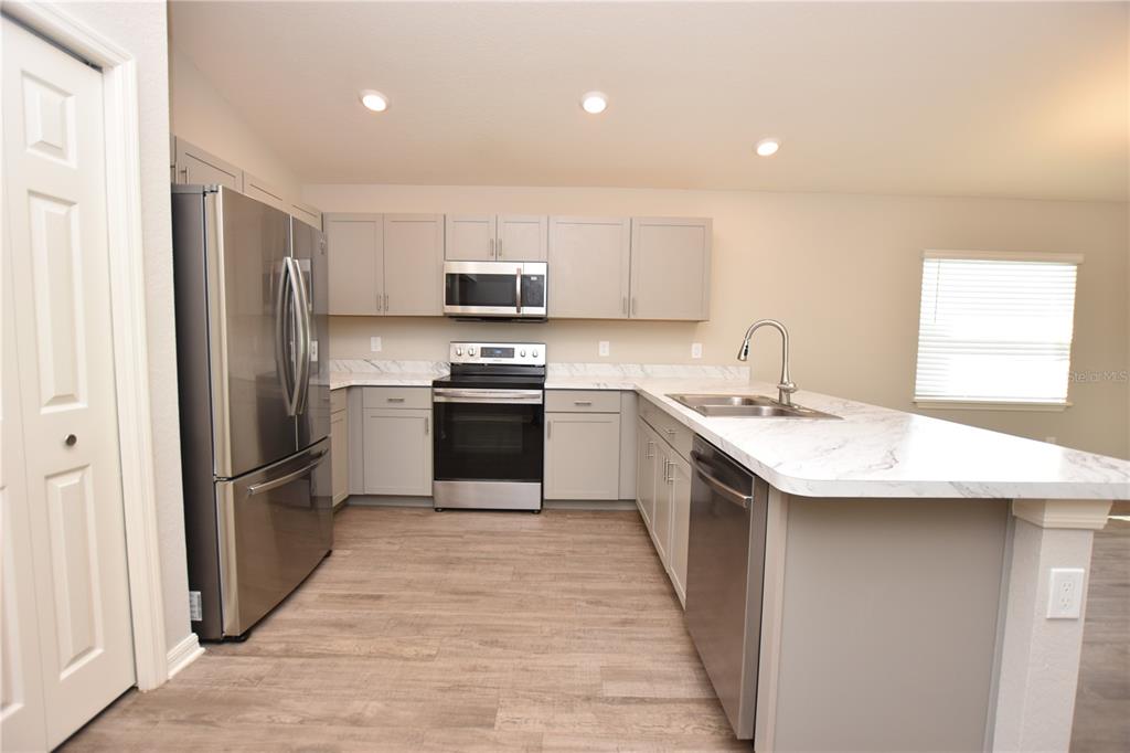 A kitchen with gray cabinets, stainless steel appliances, and white marble-patterned countertops — 372 CASCARA LANE, AUBURNDALE, FL