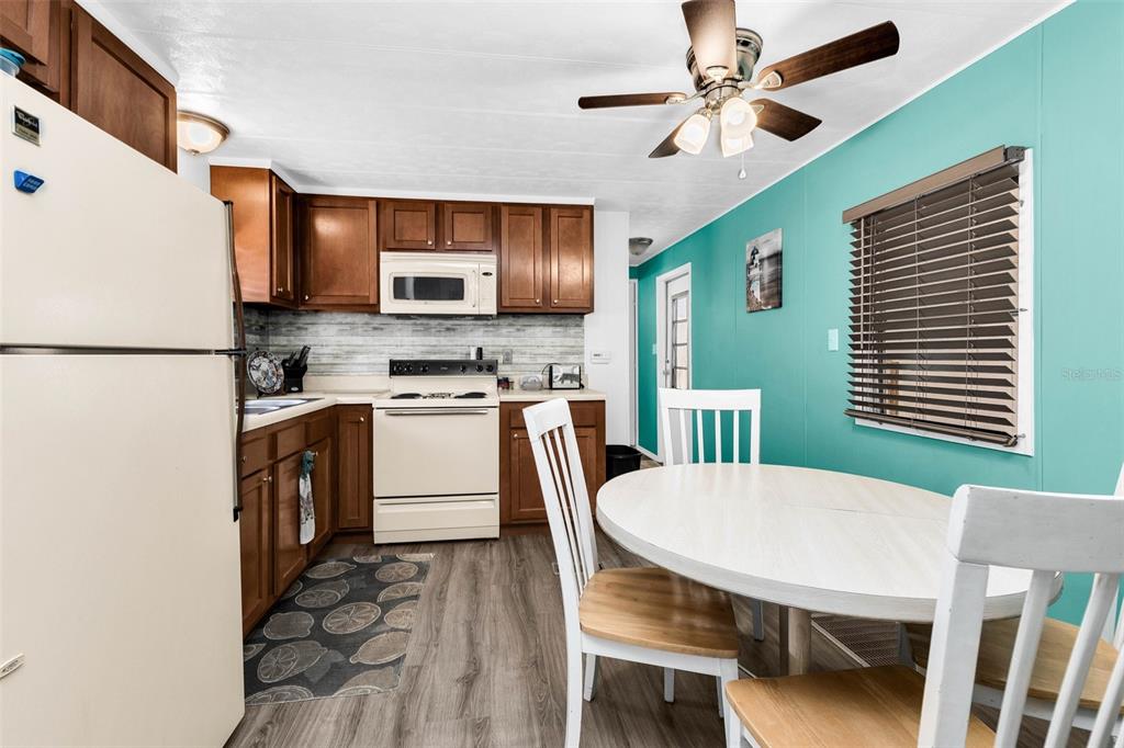 A kitchen with wood cabinets, white appliances, and a dining area with teal walls — 6442 HIKINA DRIVE, NORTH PORT, FL