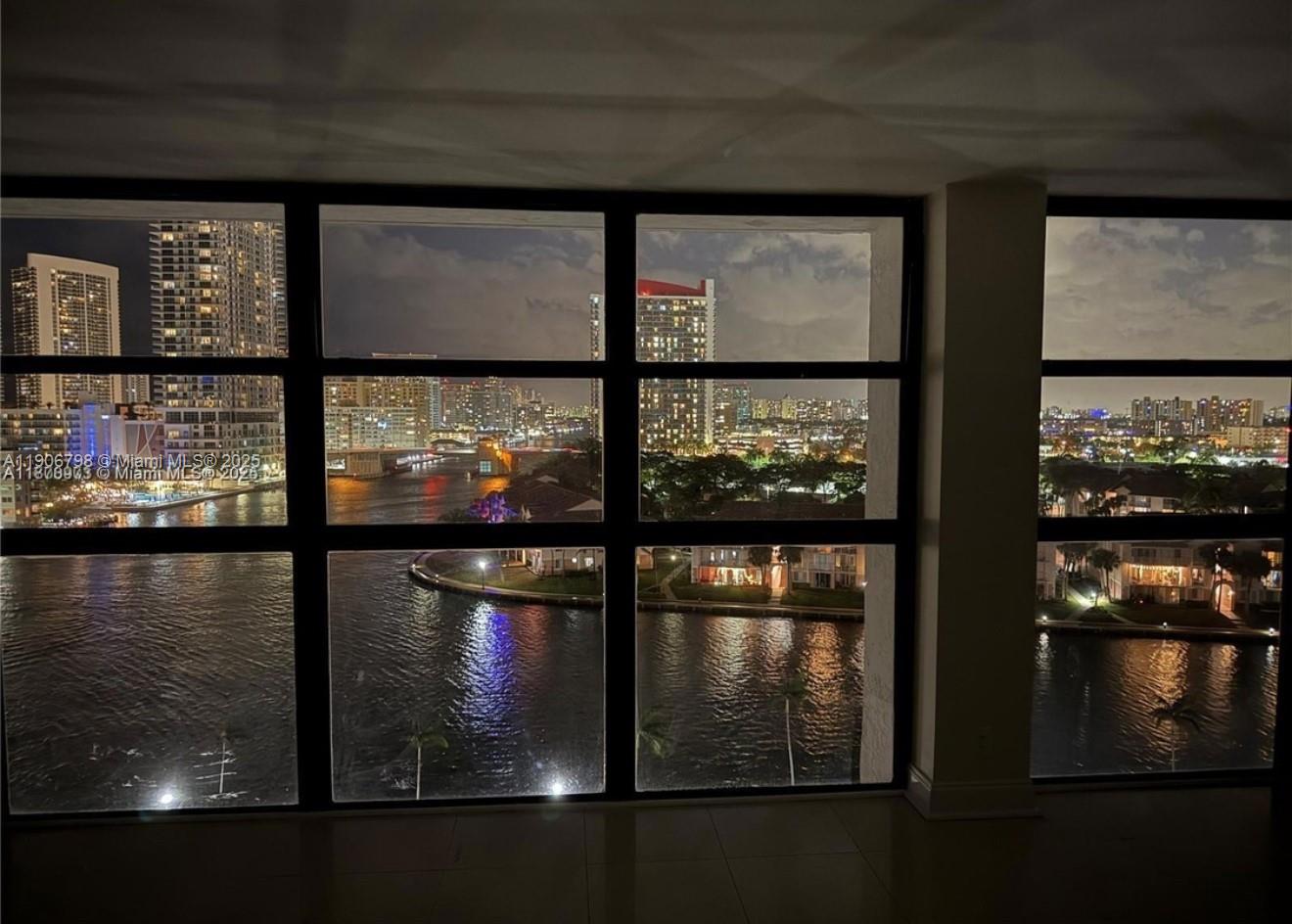A view of a city skyline and waterfront at night through a large window — 200 Leslie Dr # 1124, Hallandale Beach FL 33009, HALLANDALE BEACH, FL