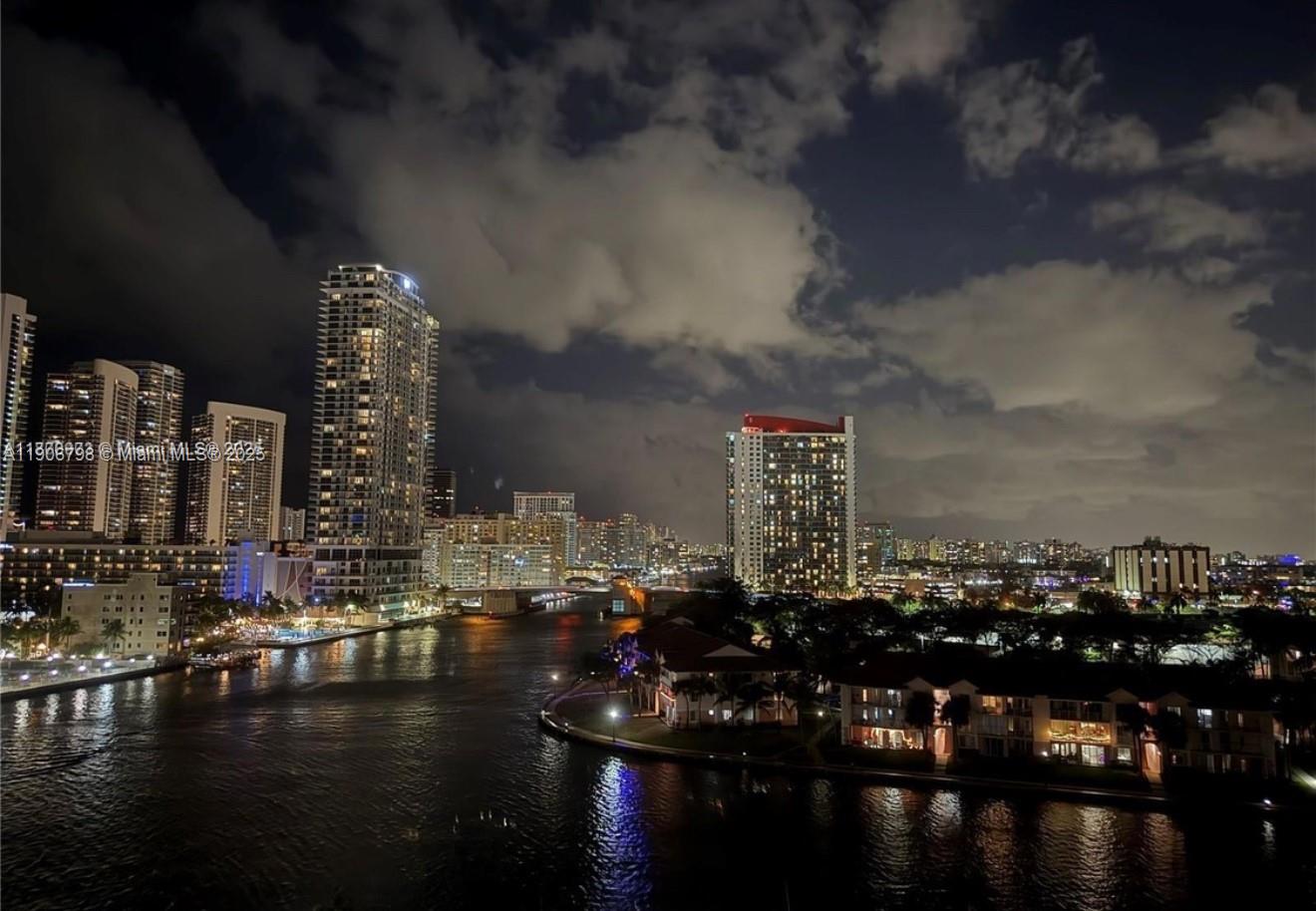 A night view of a waterfront city skyline featuring high-rise buildings and residential complexes — 200 Leslie Dr # 1124, Hallandale Beach FL 33009, HALLANDALE BEACH, FL