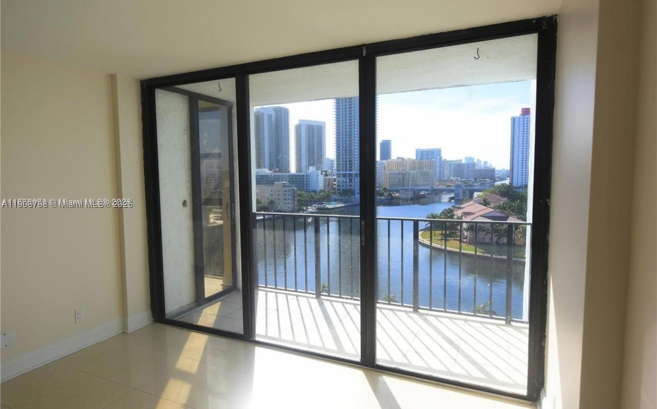 A room with light tile flooring features a large sliding glass door opening to a balcony — 200 Leslie Dr # 1124, Hallandale Beach FL 33009, HALLANDALE BEACH, FL
