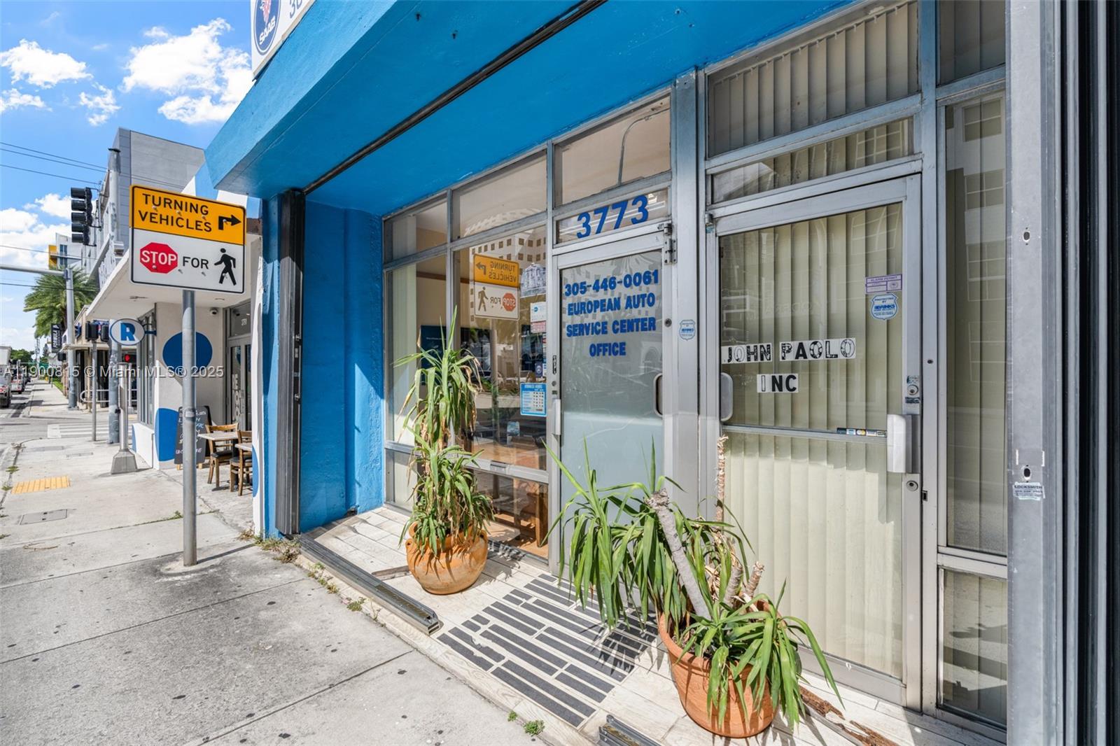The exterior of a blue commercial storefront features glass doors and potted plants on the sidewalk — 3771 Bird Rd, Miami FL 33146, MIAMI, FL