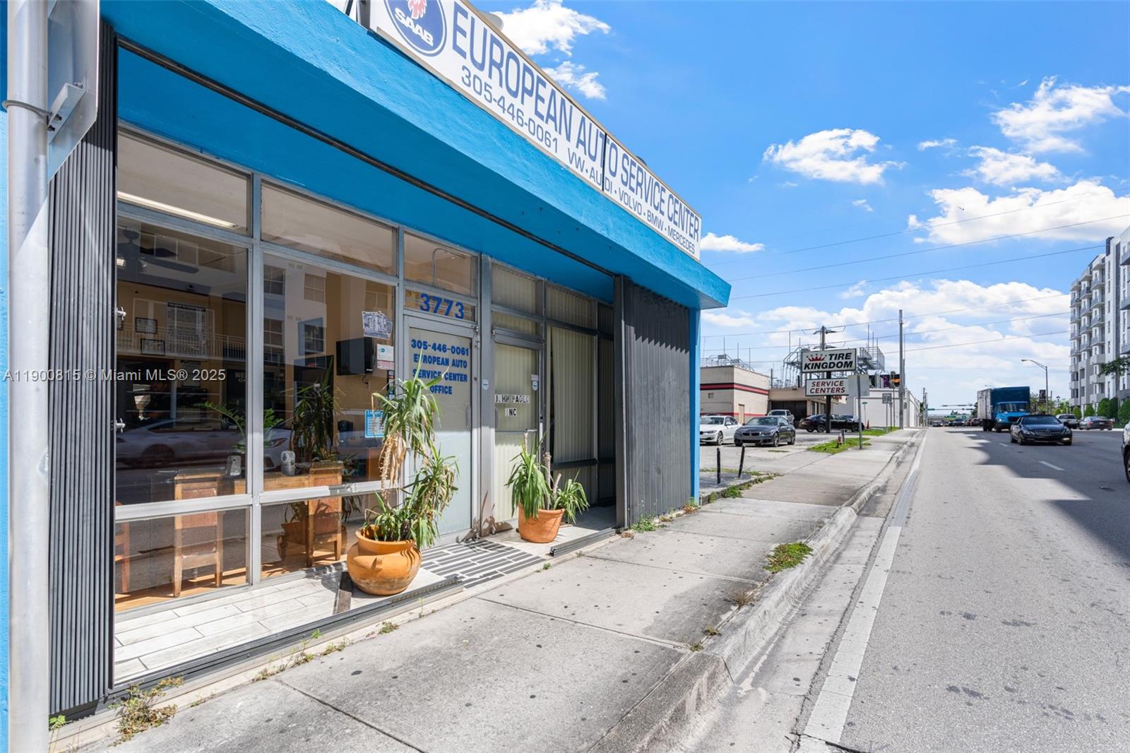 The exterior of a blue commercial building with a glass storefront and potted plants — 3771 Bird Rd, Miami FL 33146, MIAMI, FL