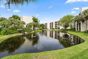 A pond sits in front of multi-story apartment buildings surrounded by palm trees and grass — 1605 Us-1 # E301, Jupiter FL 33477, JUPITER, FL