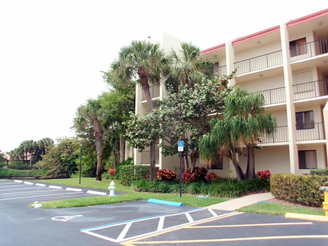 A multi-story apartment building with balconies stands next to a parking lot and palm trees — 1605 Us-1 # E301, Jupiter FL 33477, JUPITER, FL