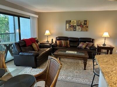 A living room features dark leather sofas, a wooden coffee table, and two side lamps — 1605 Us-1 # E301, Jupiter FL 33477, JUPITER, FL