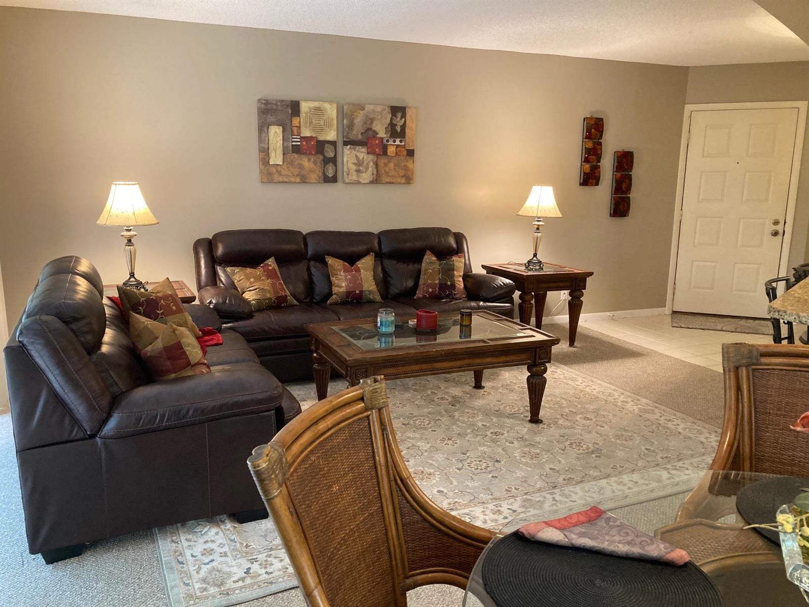 A living room features brown leather sofas, a wooden coffee table, and a patterned area rug — 1605 Us-1 # E301, Jupiter FL 33477, JUPITER, FL