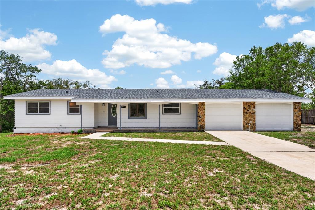A single-story house with white horizontal siding, a stone-accented garage, and a covered porch — 12071 DEEP CREEK DRIVE, SPRING HILL, FL