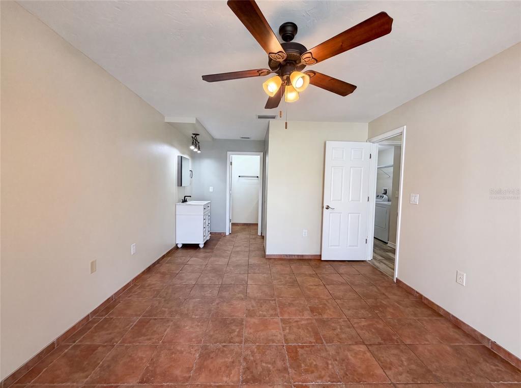 A room with brown tile flooring, a ceiling fan, a white vanity, and two doorways — 3430 55TH DRIVE E, BRADENTON, FL