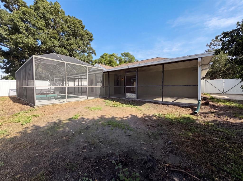 The backyard features a screened-in pool enclosure and a covered patio attached to the house — 3430 55TH DRIVE E, BRADENTON, FL