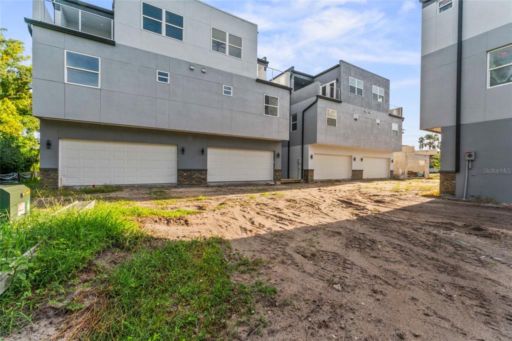 The exterior view shows modern multi-story townhomes with attached garages and an unfinished dirt driveway — 809 W LINEBAUGH AVENUE UNIT 1B, TAMPA, FL