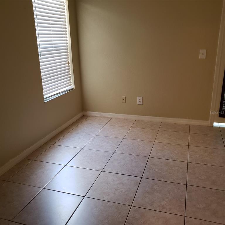 An empty room with beige walls, tiled flooring, and a window with white blinds — 5168 CONROY ROAD UNIT 11, ORLANDO, FL