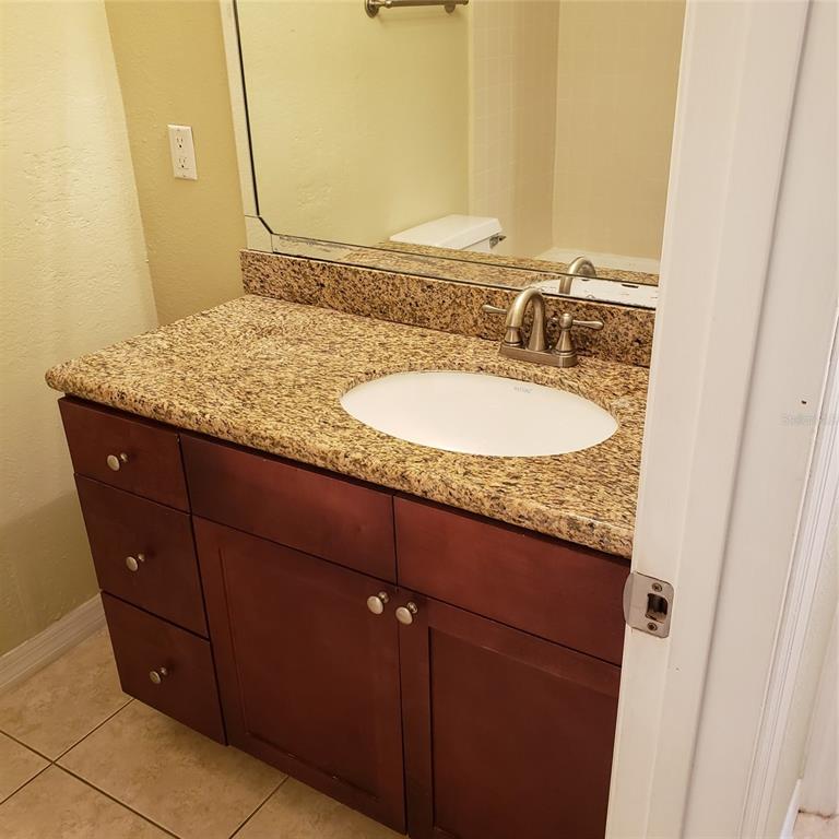 A bathroom vanity features a granite countertop, an oval sink, and dark wood cabinetry — 5168 CONROY ROAD UNIT 11, ORLANDO, FL