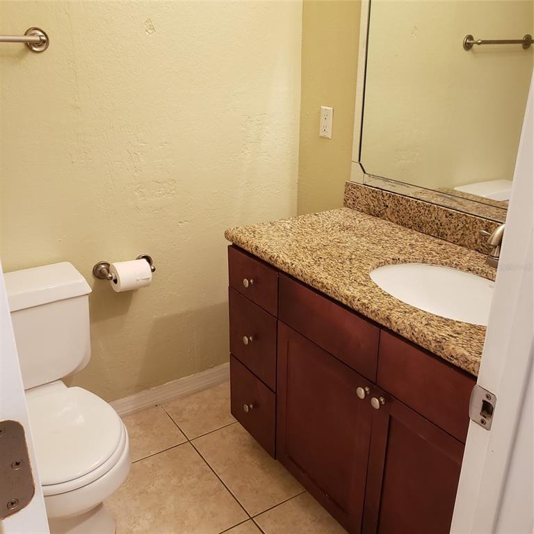 A bathroom features a granite-topped vanity, dark wood cabinets, a toilet, and tile flooring — 5168 CONROY ROAD UNIT 11, ORLANDO, FL