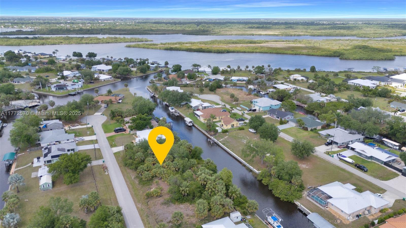 An aerial view shows a vacant, tree-covered lot situated along a residential canal — 28450 Sabal Palm Dr, Punta Gorda FL 33982, PUNTA GORDA, FL
