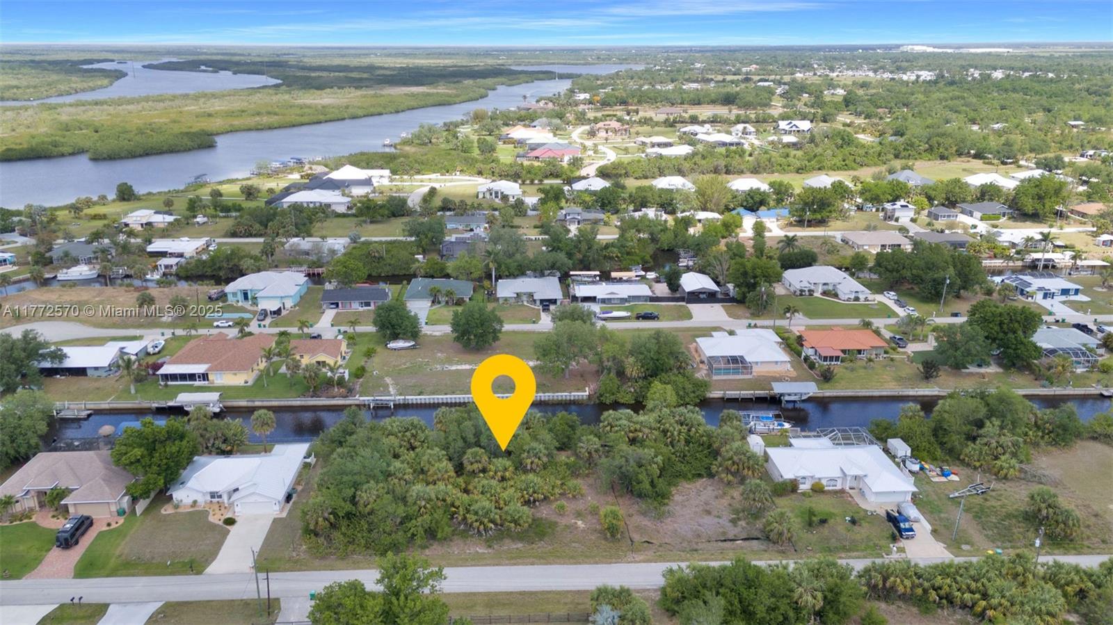 An aerial view shows a vacant, tree-covered lot situated along a residential canal — 28450 Sabal Palm Dr, Punta Gorda FL 33982, PUNTA GORDA, FL