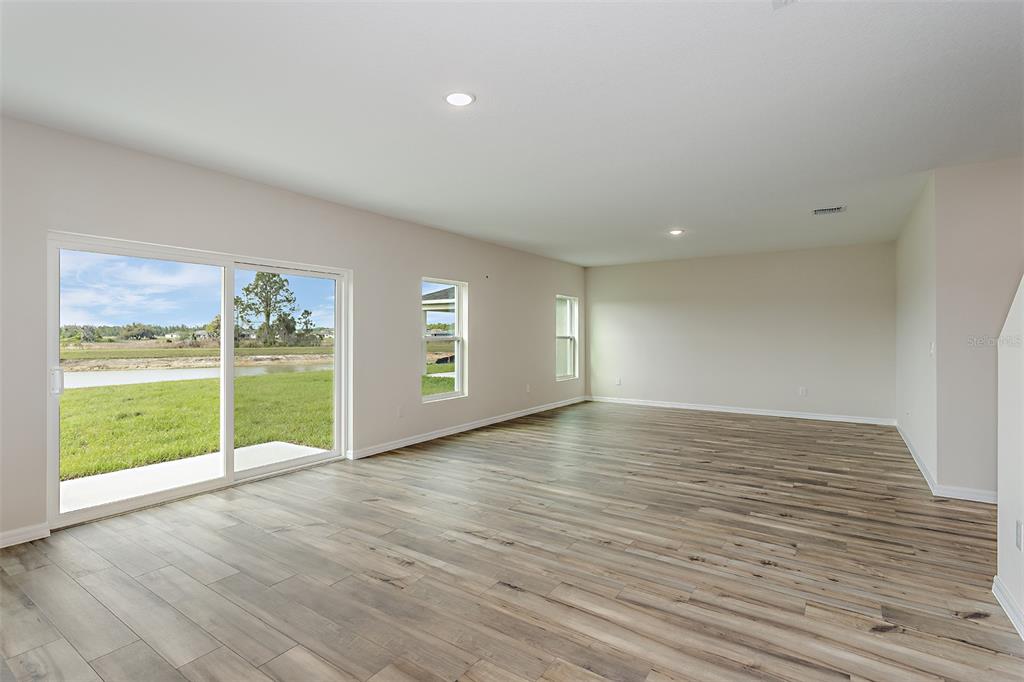 An empty living room features wood-look flooring, recessed lighting, and a sliding glass door — 1756 VANILLA STREET, HAINES CITY, FL