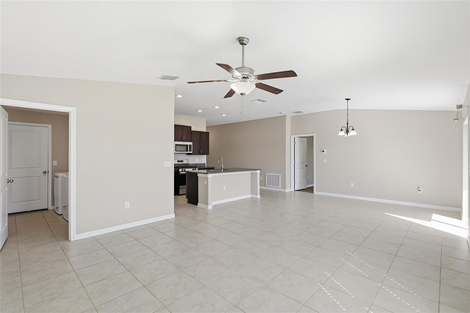 An open-concept living area features light tile flooring, a kitchen island, and a ceiling fan — 9728 Channing Hill Drive, FL 33573, FL