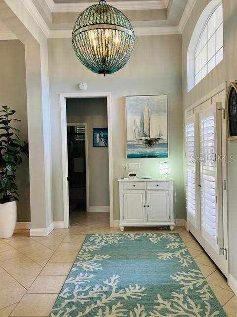 A foyer features a beaded chandelier, a white cabinet, a sailboat painting, and a coral-patterned rug — 7236 ORCHID ISLAND PLACE, BRADENTON, FL