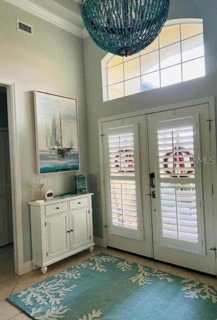An entryway features a white cabinet, a sailboat painting, a teal rug, and double glass doors — 7236 ORCHID ISLAND PLACE, BRADENTON, FL