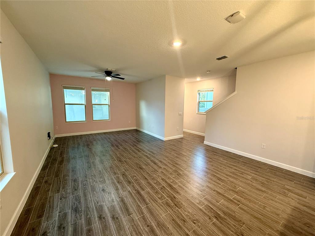 An empty living room features wood-look tile flooring, a ceiling fan, and light-colored walls — 1421 HAPPY BIRD LANE, WINTER SPRINGS, FL