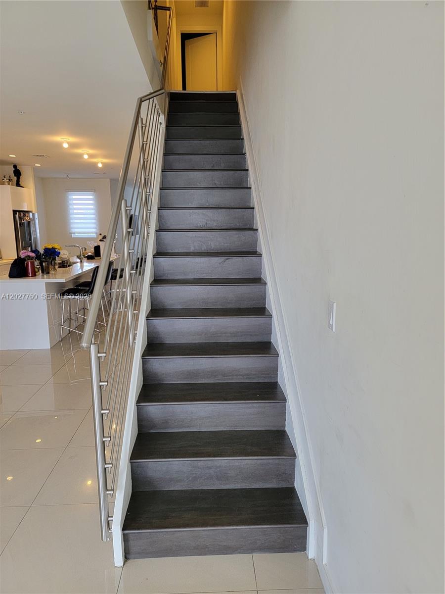 A straight staircase with dark wood treads and a metal railing leads to an upper floor — 6310 NW 103rd Pl # 202, Doral FL 33178, DORAL, FL
