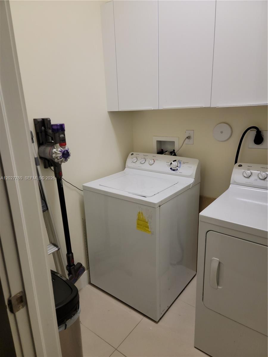 A laundry room features a white top-load washer, a dryer, and overhead storage cabinets — 6310 NW 103rd Pl # 202, Doral FL 33178, DORAL, FL
