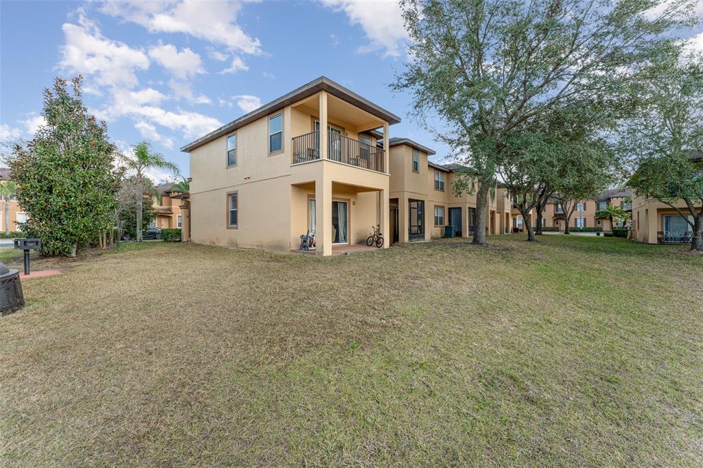 The exterior of a two-story tan townhouse features a covered patio and a second-floor balcony — 2153 CALABRIA AVENUE, DAVENPORT, FL