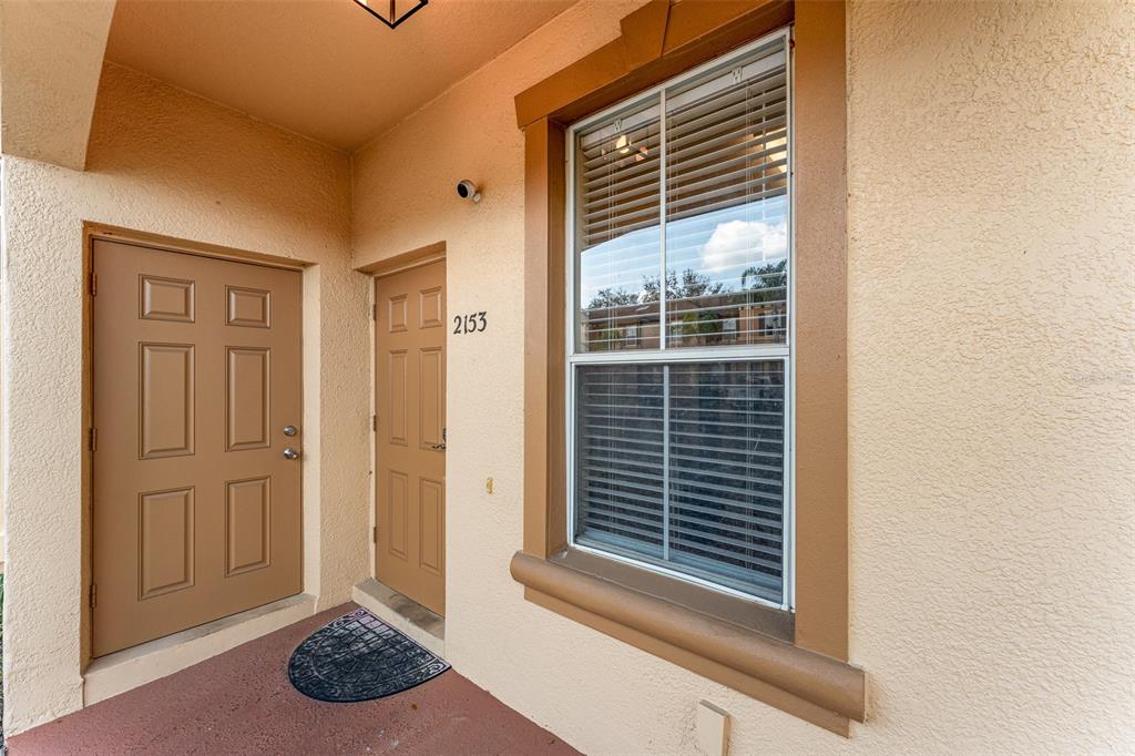 An exterior view of a building entrance featuring two tan doors and a large window — 2153 CALABRIA AVENUE, DAVENPORT, FL