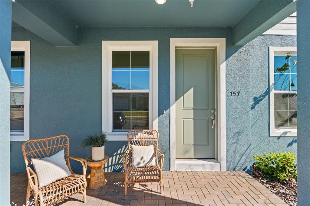 A front porch features two wicker chairs, a small side table, and a green door — 730 BLISSFUL GARDENS WAY, APOPKA, FL